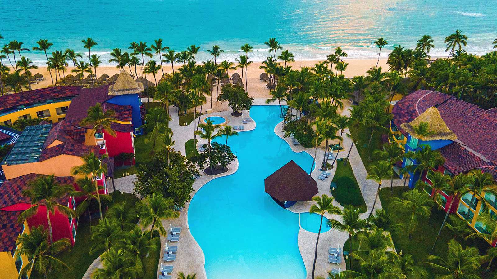 Aerial view of an all-inclusive resort in Punta Cana, with a pool, palm trees and a turquoise-water beach