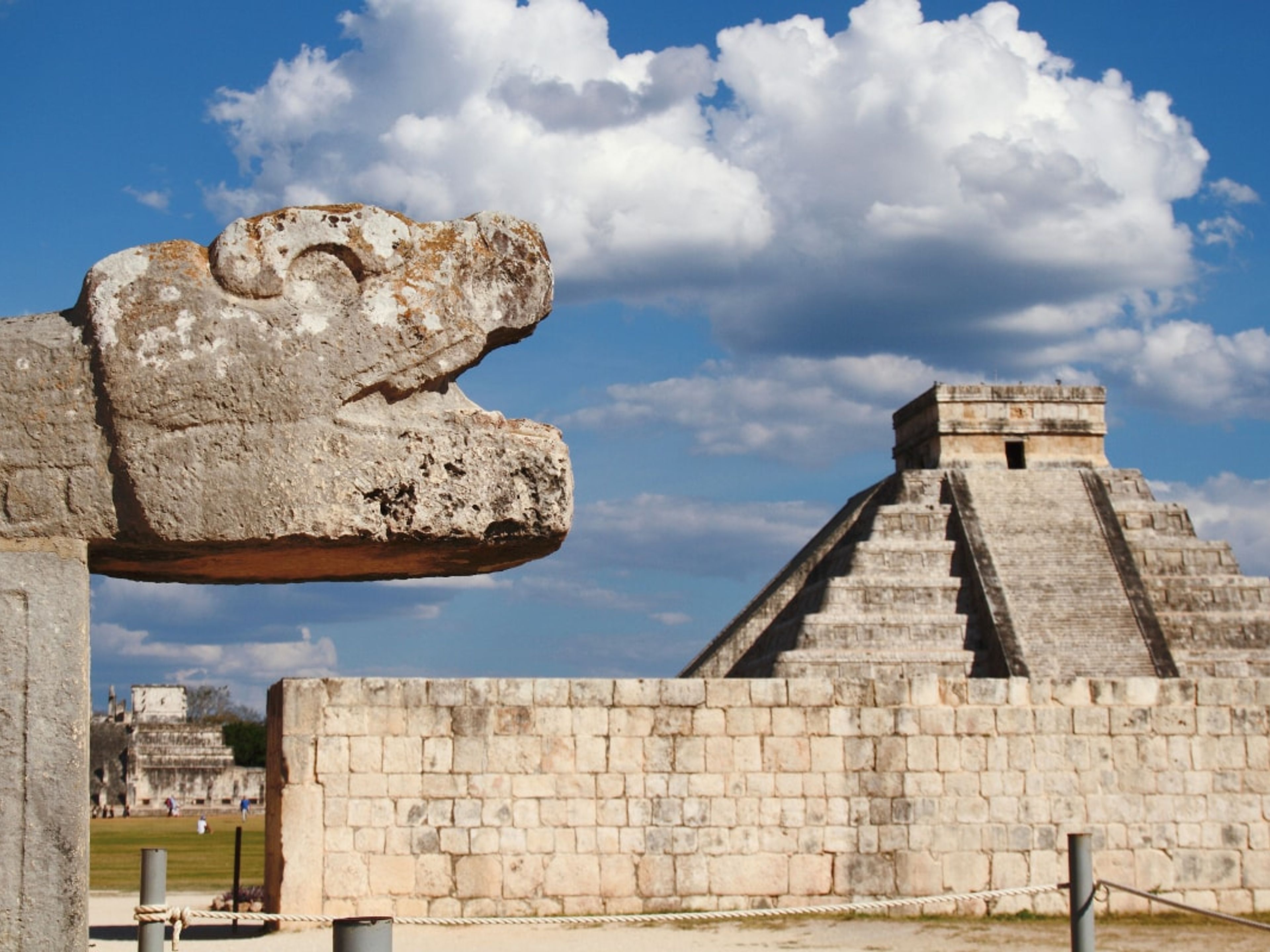Tour "Xichen Itza Deluxe". A feathered serpent sculpture at the base of one of the stairways of El Castillo, in Chichen Itza Archaeological Zone, cancun. Mexico.